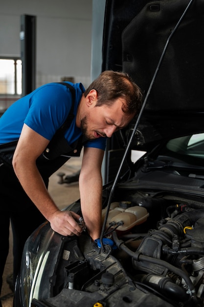 Mecânico masculino trabalhando em oficina mecânica no carro