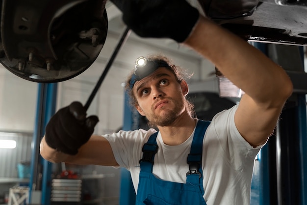 Foto grátis mecânico masculino trabalhando na loja em um carro