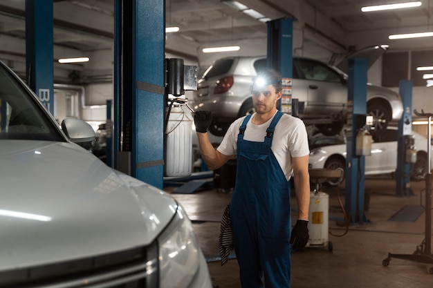 Foto grátis mecânico masculino trabalhando na loja em um carro