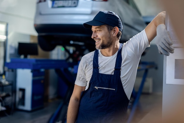 Mecânico sorridente relaxando fazendo uma pausa no trabalho na oficina de automóveis