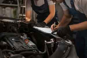 Foto grátis mecânicos masculinos e femininos trabalhando na loja em um carro