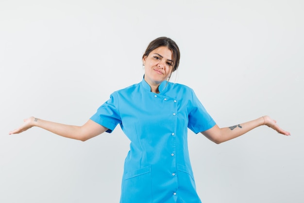 Médica abrindo os braços para os lados com uniforme azul e parecendo sonhadora