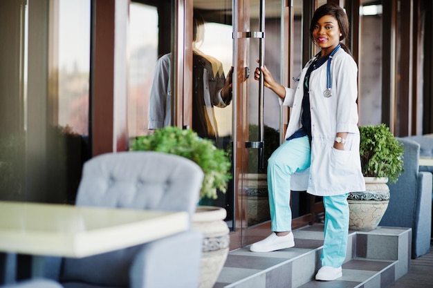 Médica afro-americana com estetoscópio posada na clínica moderna