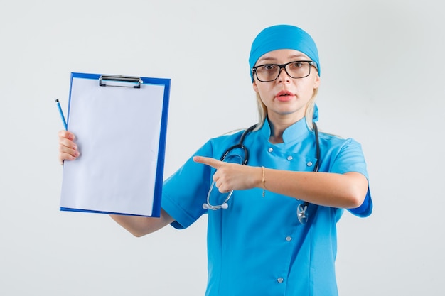 Médica apontando o dedo para a prancheta com uniforme azul