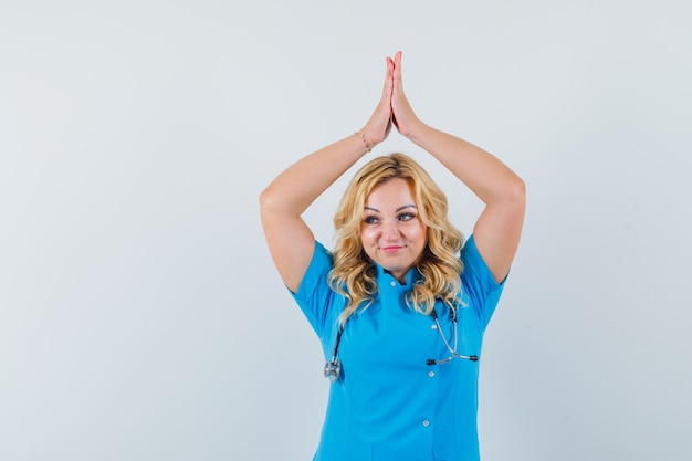 Médica batendo palmas na cabeça com uniforme azul e parecendo satisfeita.