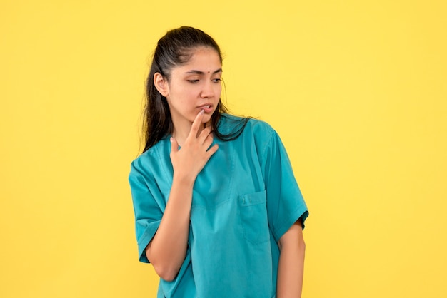 Médica bonita e atenciosa de frente em pé sobre fundo amarelo