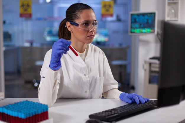 Médica cientista segurando vacutainer médico com experiência em tipagem sanguínea