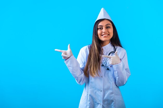 Médica com estetoscópio apontando para algo e sorrindo.