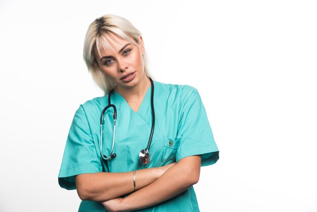 Médica com estetoscópio cruzando os braços em fundo branco. Foto de alta qualidade