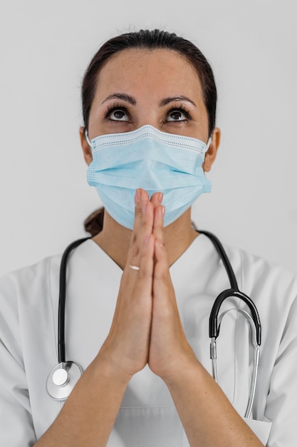 Médica com estetoscópio orando