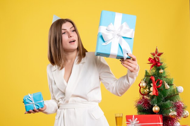 Médica com vista frontal segurando presentes de Natal