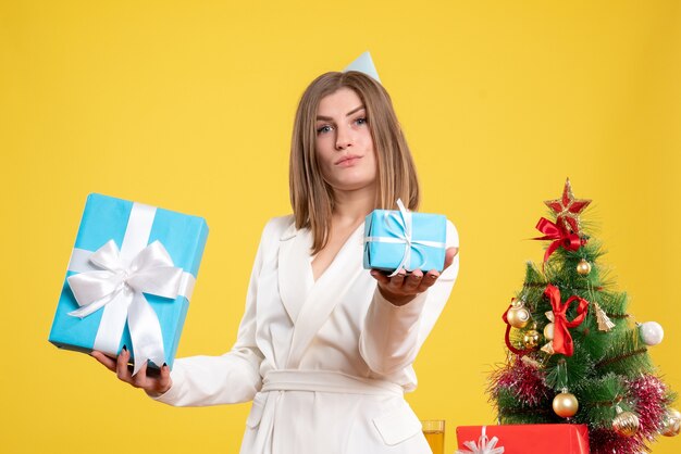 Médica com vista frontal segurando presentes de Natal