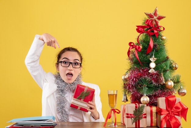 Médica com vista frontal segurando um presente de natal