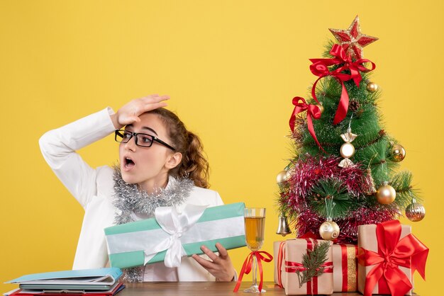 Médica com vista frontal segurando um presente de natal