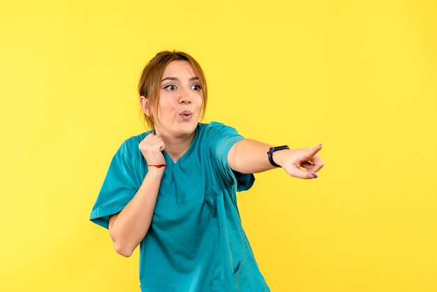 Médica de frente apontando para o espaço amarelo