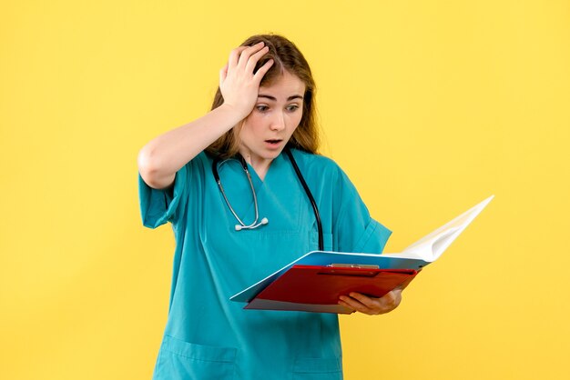 Médica de frente com análises sobre fundo amarelo, enfermeira, saúde do hospital