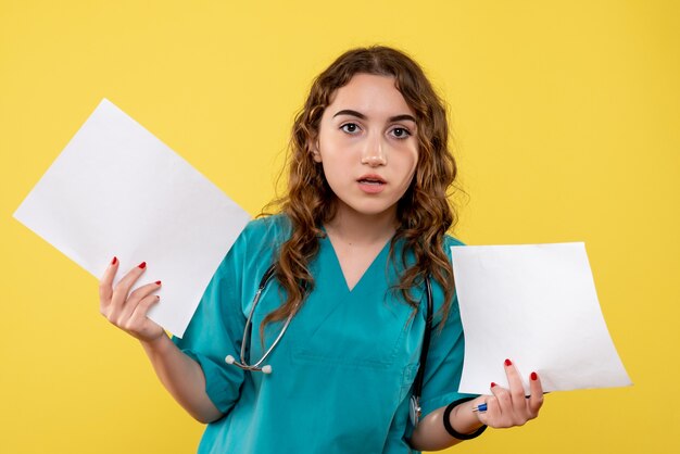 Médica de frente com camiseta médica segurando a análise do papel, vírus pandêmico da saúde covid-19, emoções uniformes