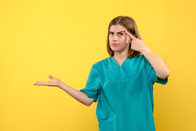 Médica de frente com expressão calma no espaço amarelo