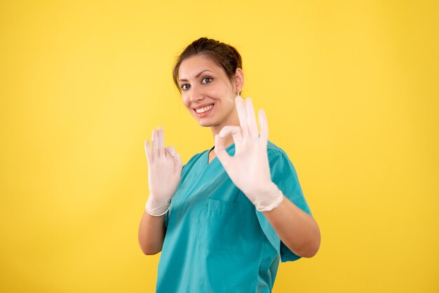 Médica de frente com luvas em fundo amarelo