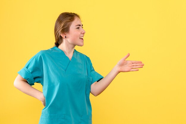 Médica de frente falando com alguém sobre o vírus da cor do hospital de saúde de fundo amarelo