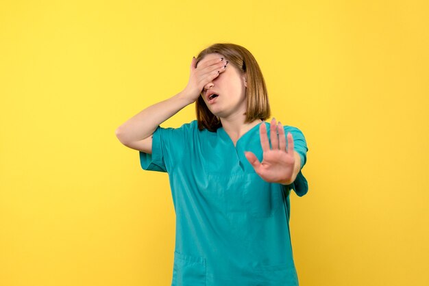 Médica de frente fechando os olhos no espaço amarelo