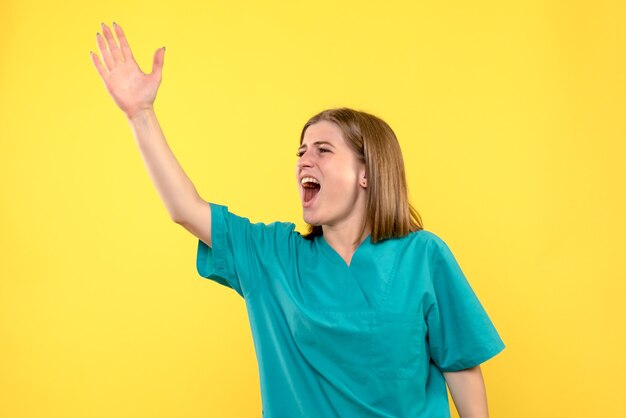 Médica de frente gritando alto no espaço amarelo