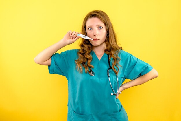 Médica de frente medindo temperatura no espaço amarelo