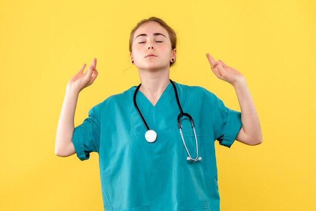 Médica de frente meditando sobre fundo amarelo médico hospital saúde emoção