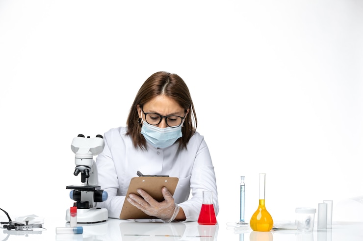 Foto grátis médica de frente para o terno branco com máscara devido a estar escrevendo algo no espaço em branco