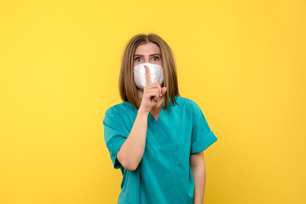 Médica de frente pedindo para ficar quieta no espaço amarelo