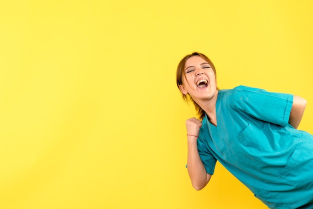 Médica de frente regozijando-se no espaço amarelo