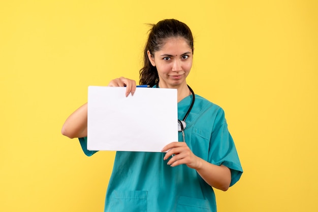 Médica de frente segurando papéis em pé