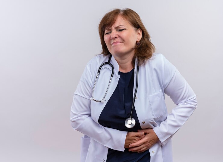 Foto grátis médica de meia-idade desapontada vestindo túnica médica e estetoscópio com as mãos nos rins sofrendo de dores renais na parede branca isolada com espaço de cópia