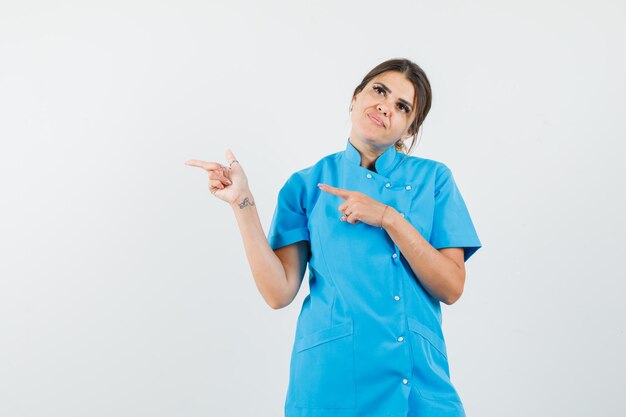 Médica de uniforme azul apontando para o lado e parecendo pensativa