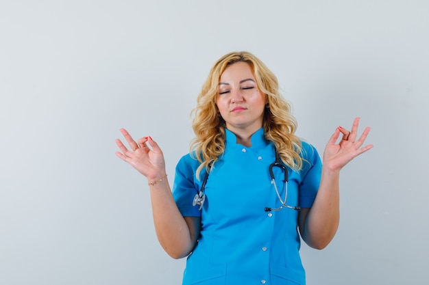 Médica de uniforme azul meditando e olhando para o foco