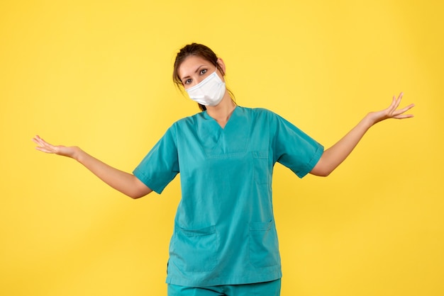 Médica de vista frontal com camisa médica e máscara em fundo amarelo