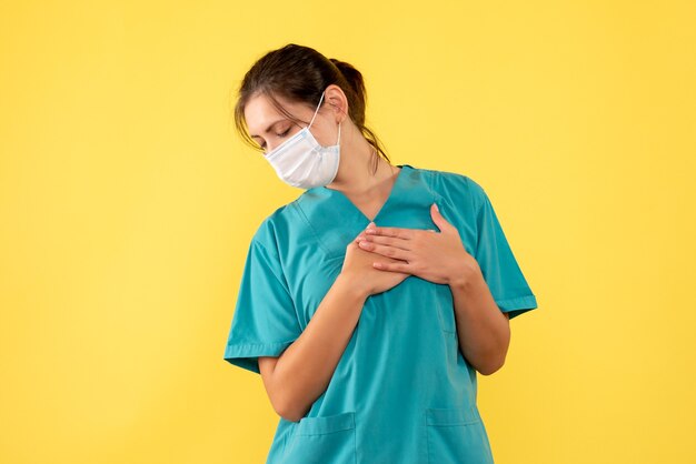 Médica de vista frontal com camisa médica e máscara em fundo amarelo