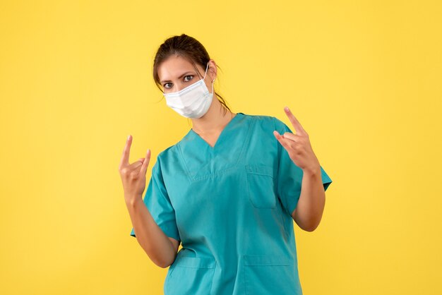 Médica de vista frontal com camisa médica e máscara em fundo amarelo