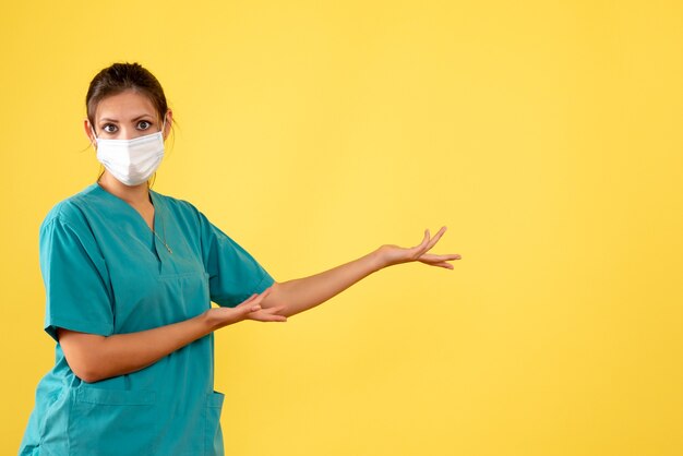 Médica de vista frontal com camisa médica e máscara estéril em fundo amarelo