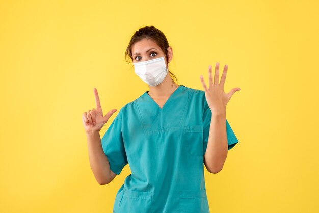Médica de vista frontal com camisa médica e máscara estéril em fundo amarelo