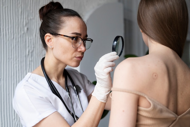 Médica diagnosticando um melanoma no corpo de uma paciente do sexo feminino