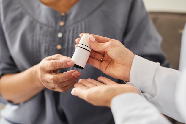 Médica do centro de recuperação da Covid dando frasco de comprimidos para pacientes idosos