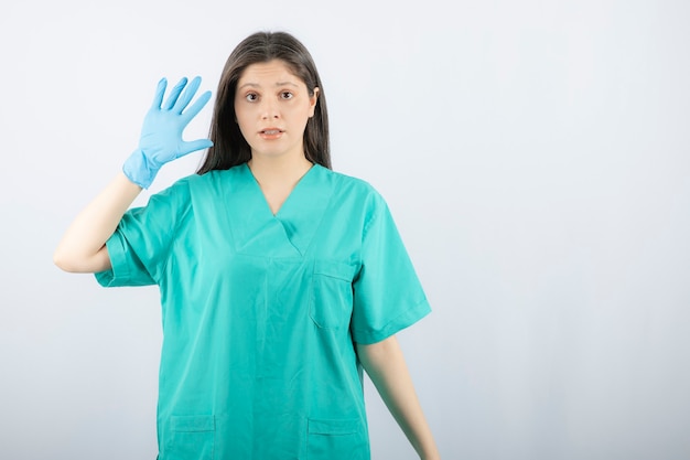 Médica em luvas médicas, mostrando as mãos em branco.