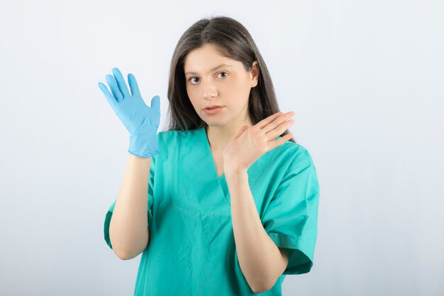 Médica em luvas médicas, mostrando as mãos em branco.