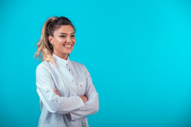 Médica em uniforme branco sorrindo.