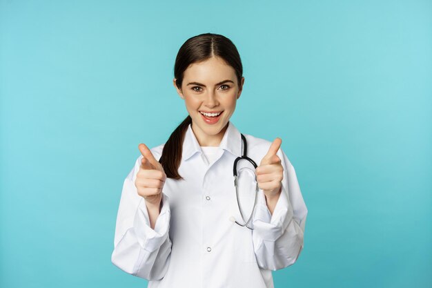 Médica entusiasmada sorrindo apontando dedos para a câmera parabenizando convidando os pacientes para c...