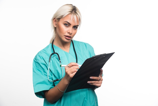 Médica, escrevendo algo na área de transferência com a caneta sobre fundo branco. Foto de alta qualidade