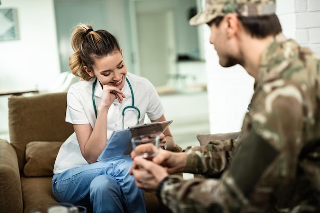 Médica feliz lendo dados médicos de um soldado enquanto tem aconselhamento em sua casa