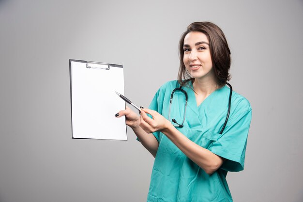 Médica mostrando a área de transferência em fundo cinza. foto de alta qualidade