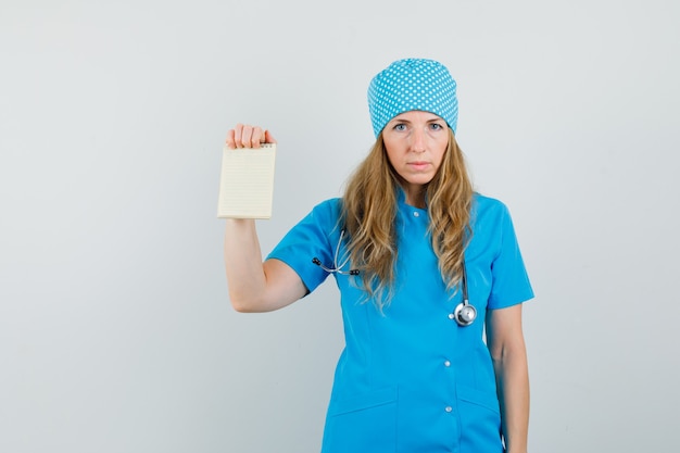 Médica mostrando caderno de uniforme azul